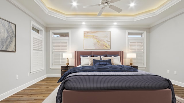 bedroom featuring hardwood / wood-style flooring, a raised ceiling, ceiling fan, and ornamental molding