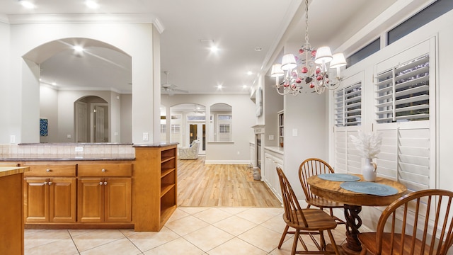 kitchen featuring backsplash, ceiling fan with notable chandelier, crown molding, pendant lighting, and light tile patterned flooring