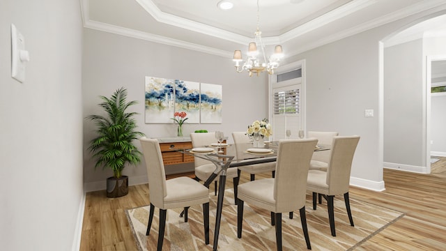 dining room featuring light hardwood / wood-style floors, a raised ceiling, crown molding, and a notable chandelier