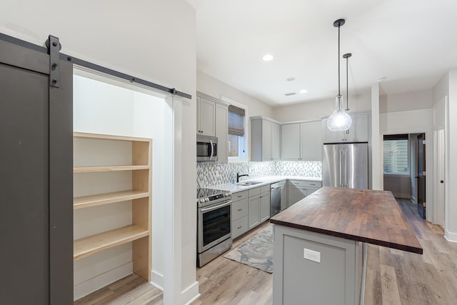 kitchen featuring gray cabinetry, wood counters, a center island, hanging light fixtures, and appliances with stainless steel finishes