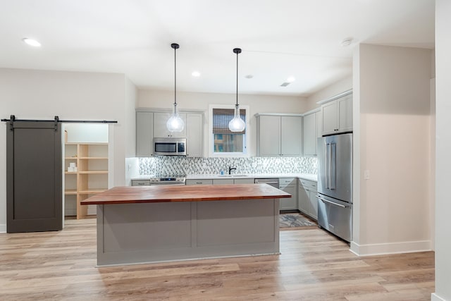 kitchen with sink, stainless steel appliances, a barn door, wooden counters, and a kitchen island