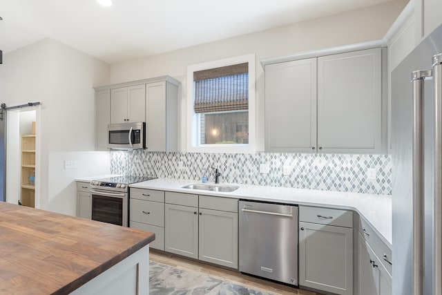 277 Edens Landing Cir, Santa Rosa Beach, FL 32459 - kitchen featuring appliances with stainless steel finishes, gray cabinetry, tasteful backsplash, and a barn door
