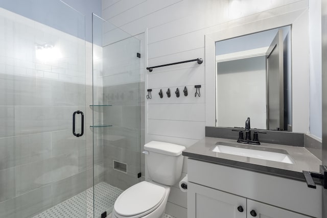 bathroom featuring vanity, toilet, a shower with door, and tile walls