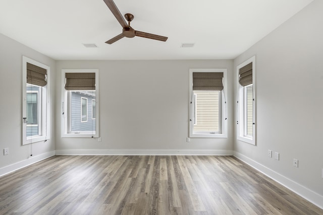 unfurnished room with a wealth of natural light, hardwood / wood-style floors, and ceiling fan