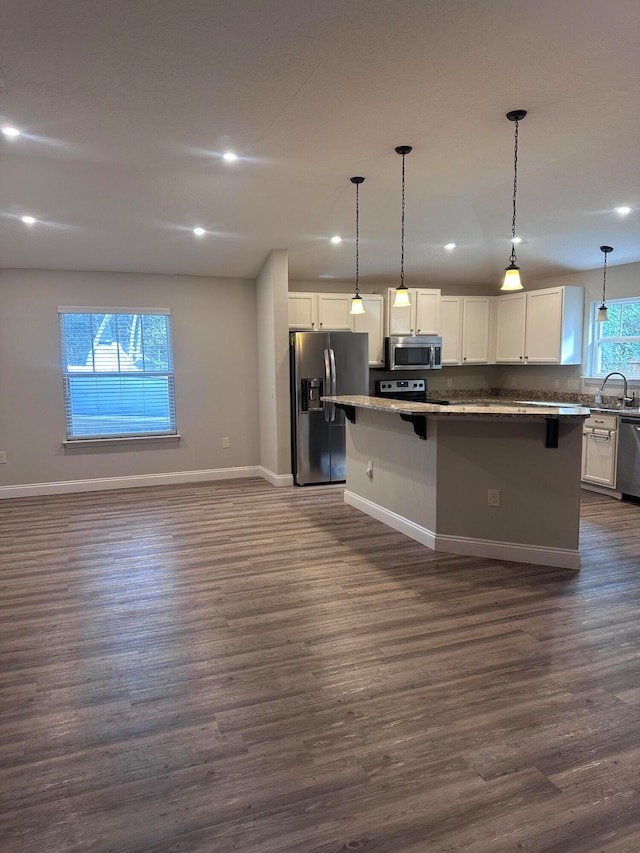 kitchen featuring stainless steel appliances, decorative light fixtures, white cabinets, a center island, and dark hardwood / wood-style floors