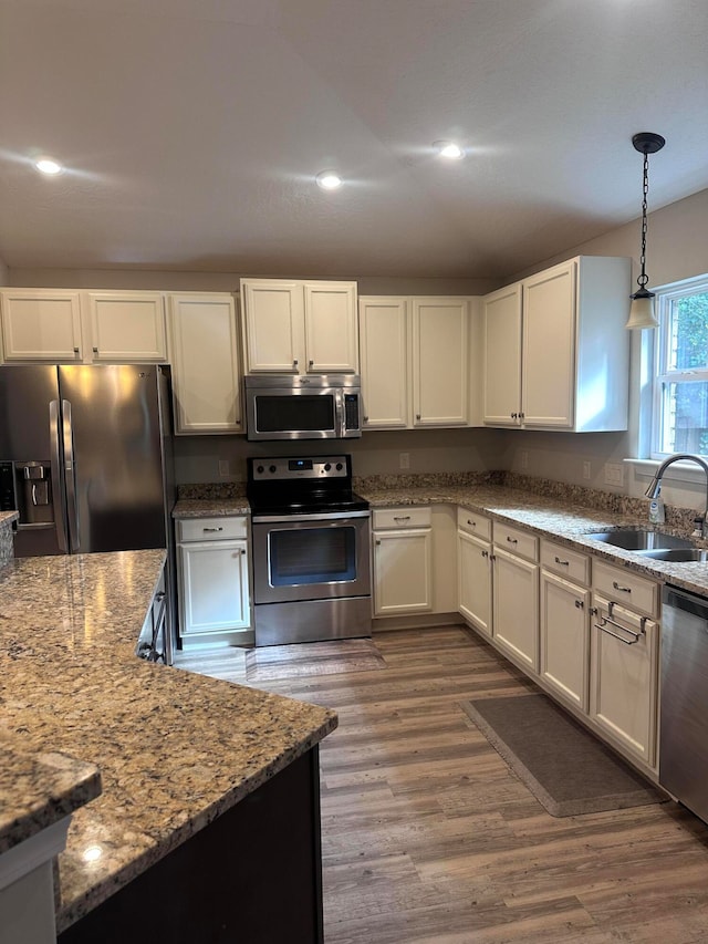 kitchen with white cabinetry, sink, hardwood / wood-style floors, pendant lighting, and appliances with stainless steel finishes