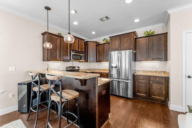 kitchen featuring kitchen peninsula, appliances with stainless steel finishes, dark wood-type flooring, decorative light fixtures, and a breakfast bar area