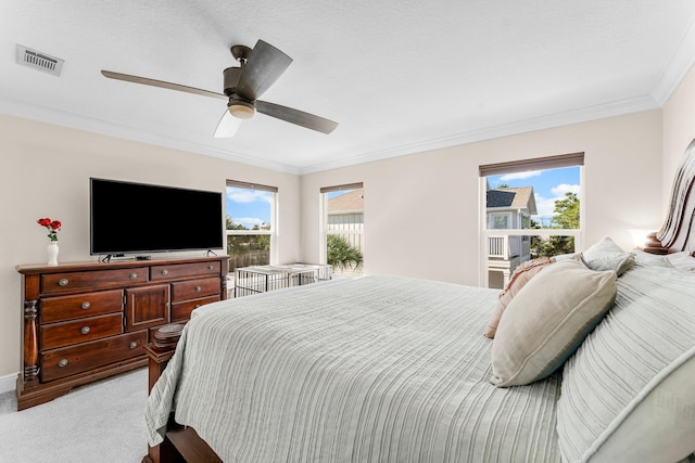 carpeted bedroom with ceiling fan, ornamental molding, and multiple windows