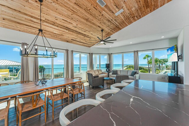 dining area with hardwood / wood-style floors, a water view, ceiling fan with notable chandelier, and high vaulted ceiling