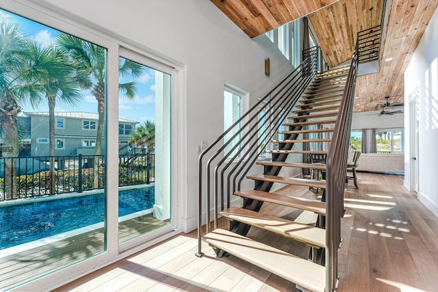 staircase with ceiling fan, hardwood / wood-style floors, a towering ceiling, and wood ceiling