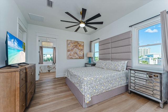 bedroom featuring ceiling fan, light hardwood / wood-style floors, and multiple windows