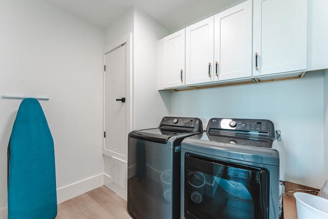 washroom with cabinets, light wood-type flooring, and washing machine and dryer