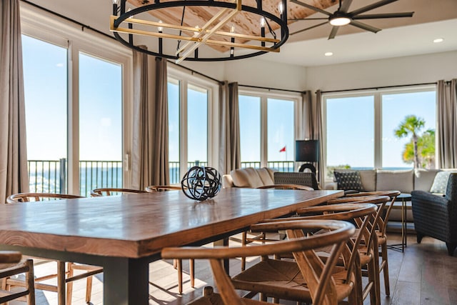 dining space featuring a water view, wood-type flooring, and ceiling fan with notable chandelier