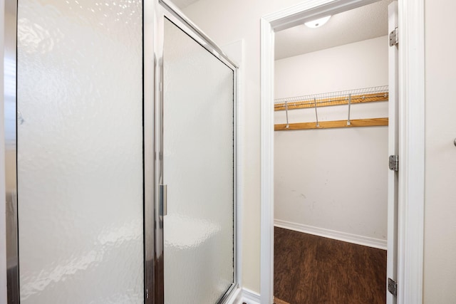 bathroom with hardwood / wood-style flooring and a shower with shower door