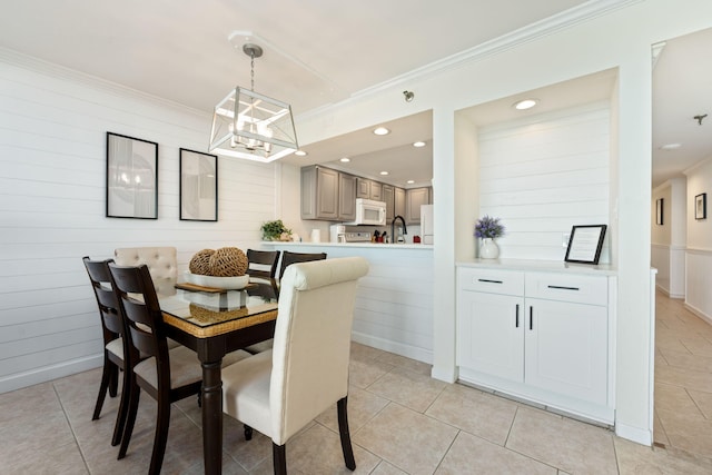 dining area featuring sink, ornamental molding, light tile patterned flooring, and a notable chandelier