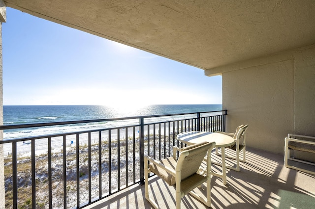 balcony with a water view and a view of the beach