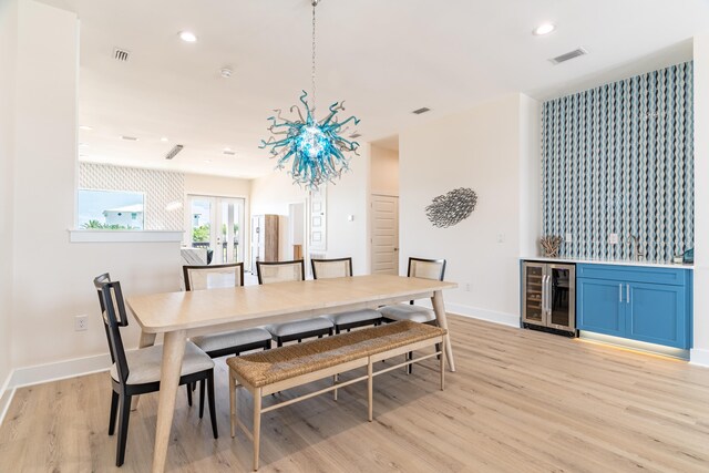 dining space with light hardwood / wood-style floors, beverage cooler, and bar area