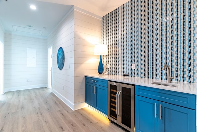 bar with sink, hanging light fixtures, wine cooler, blue cabinets, and light wood-type flooring