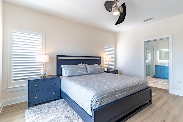 bedroom featuring ensuite bathroom, light hardwood / wood-style flooring, ceiling fan, and sink