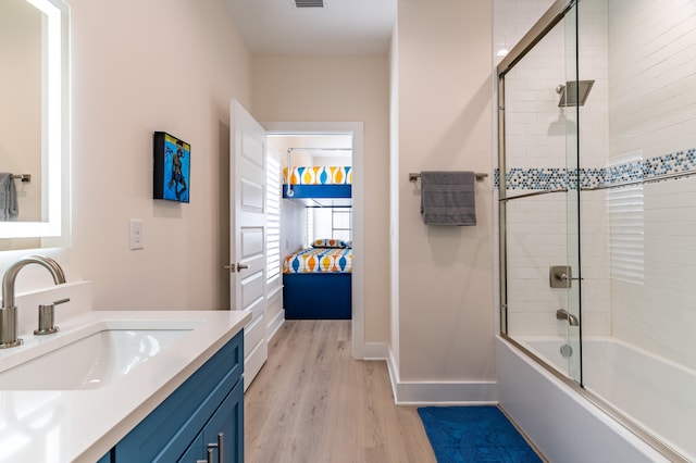 bathroom with hardwood / wood-style floors, vanity, and enclosed tub / shower combo