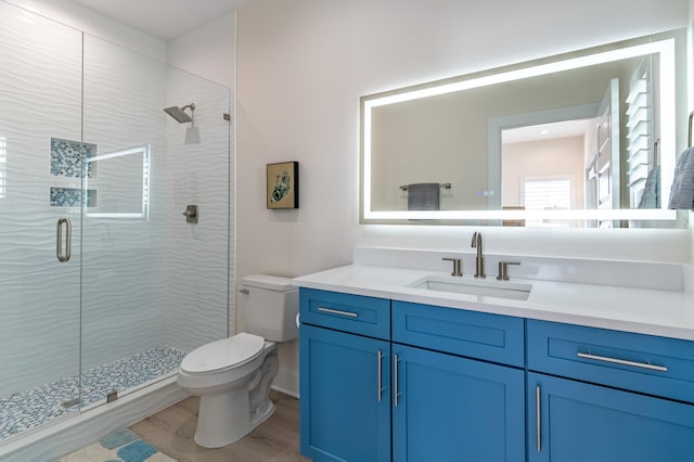 bathroom with toilet, vanity, a shower with door, and hardwood / wood-style flooring