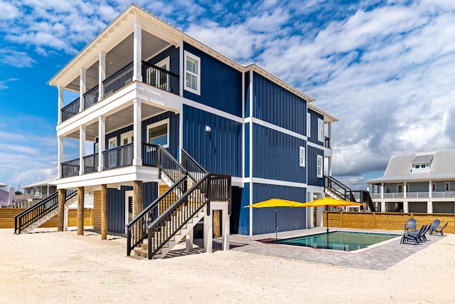 back of property featuring a patio area, a balcony, and a fenced in pool