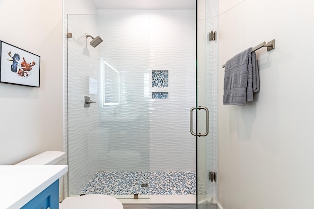 bathroom featuring vanity, an enclosed shower, and toilet