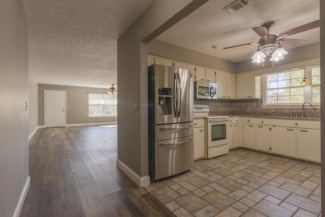 kitchen featuring decorative backsplash, a textured ceiling, stainless steel appliances, and plenty of natural light