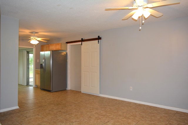 spare room with a textured ceiling, a barn door, light tile patterned floors, and ceiling fan