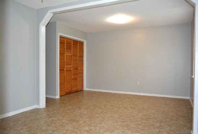 empty room with light tile patterned floors and a textured ceiling