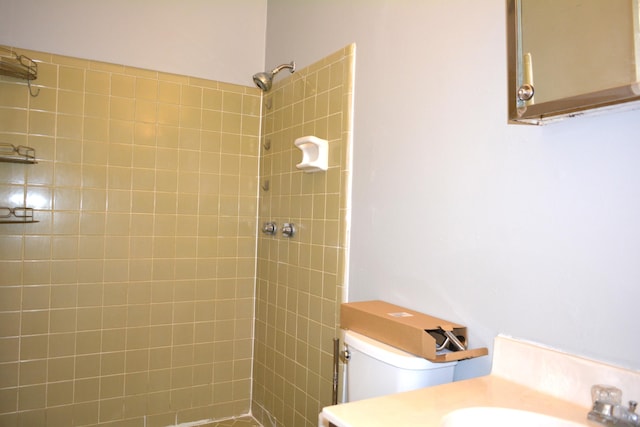 bathroom with a tile shower, sink, and toilet