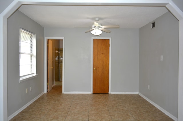 tiled spare room with ceiling fan