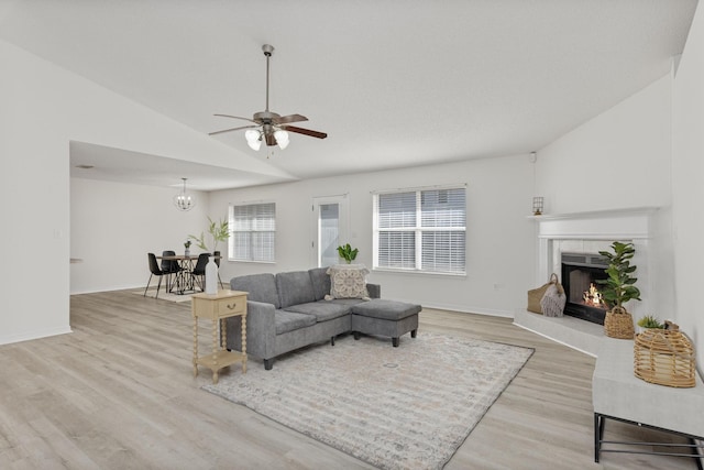 living room featuring a tile fireplace, light hardwood / wood-style flooring, a wealth of natural light, and vaulted ceiling