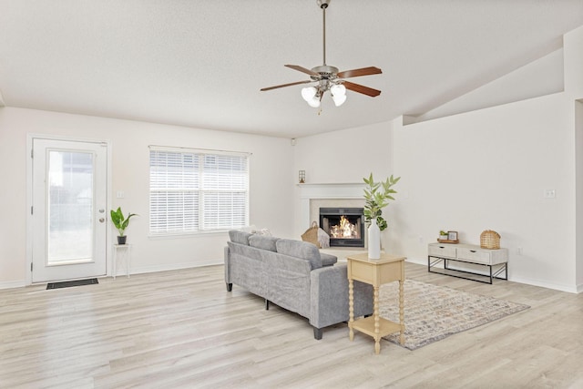 living room featuring ceiling fan, lofted ceiling, and light hardwood / wood-style flooring