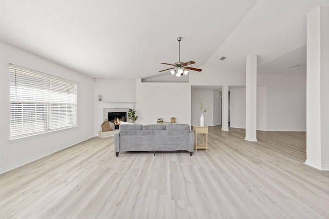 living room with ceiling fan, light hardwood / wood-style floors, and vaulted ceiling