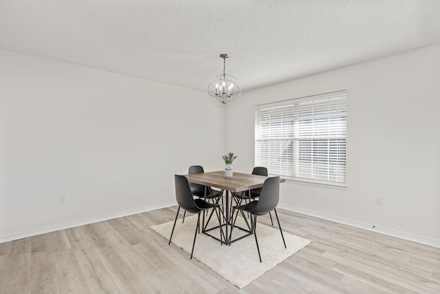 dining room with a notable chandelier, light hardwood / wood-style floors, and a textured ceiling