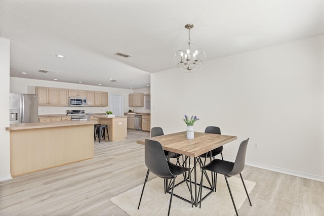 dining room featuring a notable chandelier, light hardwood / wood-style floors, and a textured ceiling