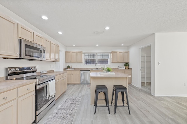 kitchen featuring stainless steel appliances, a kitchen island, a breakfast bar area, and light hardwood / wood-style flooring