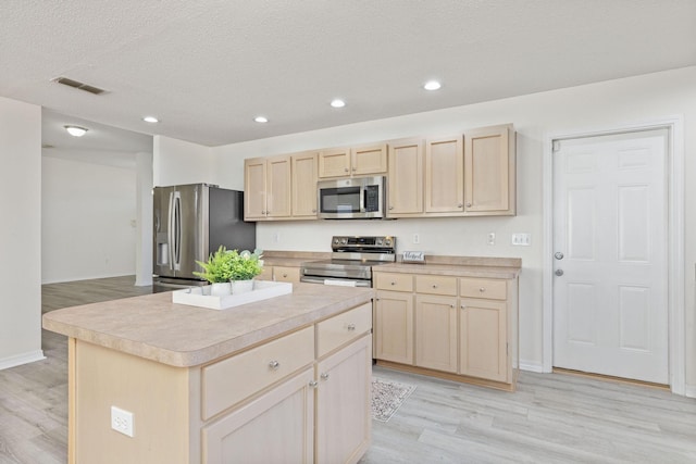 kitchen with a center island, stainless steel appliances, and light hardwood / wood-style floors