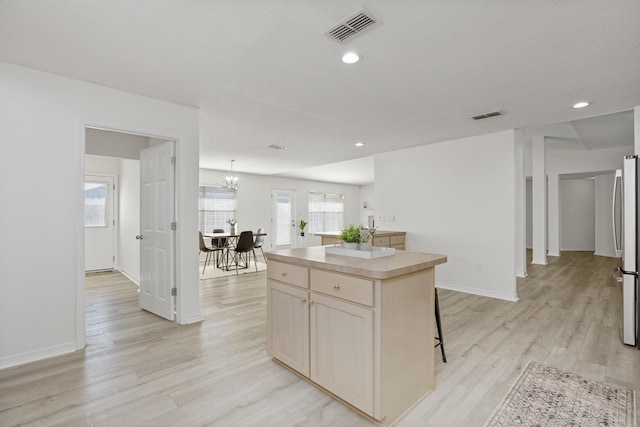 kitchen featuring a center island, a kitchen bar, light hardwood / wood-style floors, and a wealth of natural light