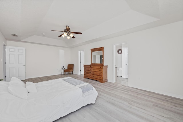 bedroom with a textured ceiling, a raised ceiling, ceiling fan, light hardwood / wood-style floors, and lofted ceiling