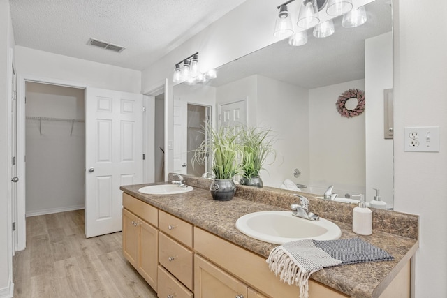 bathroom with vanity, hardwood / wood-style floors, a textured ceiling, and a washtub