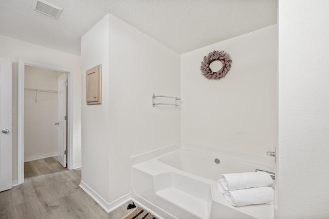 bathroom with hardwood / wood-style flooring, a washtub, and a textured ceiling