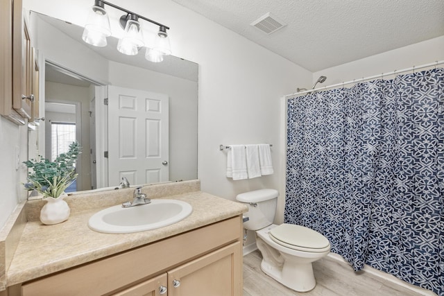 bathroom featuring a textured ceiling, vanity, hardwood / wood-style flooring, and toilet