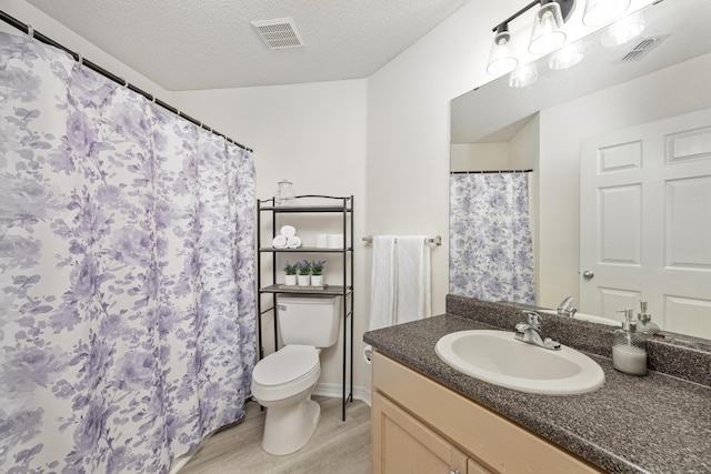 bathroom featuring vanity, toilet, wood-type flooring, and a textured ceiling