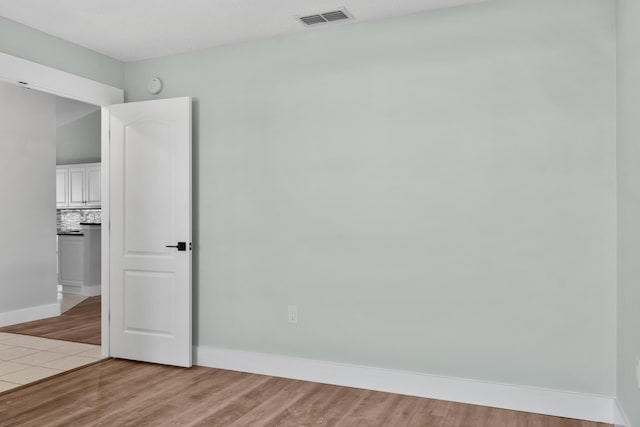 unfurnished room with a textured ceiling and light wood-type flooring