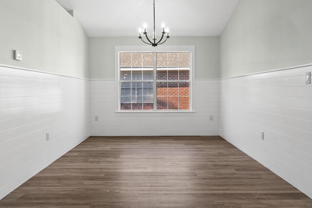 unfurnished dining area with a chandelier and hardwood / wood-style flooring