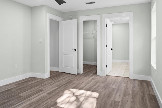 unfurnished bedroom featuring a walk in closet, light wood-type flooring, and a closet