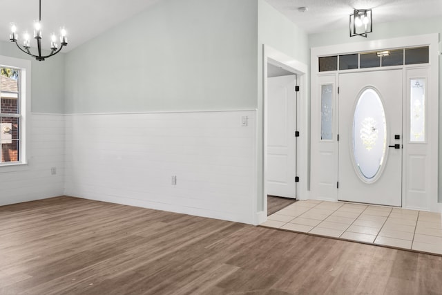 entrance foyer featuring light hardwood / wood-style flooring, a textured ceiling, and a notable chandelier