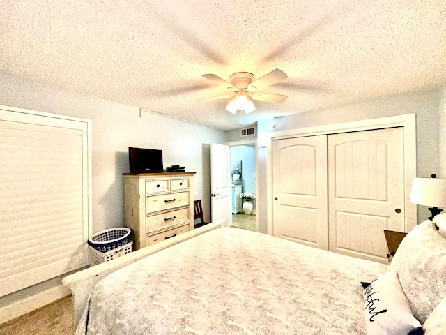 bedroom with ceiling fan, a closet, carpet, and a textured ceiling